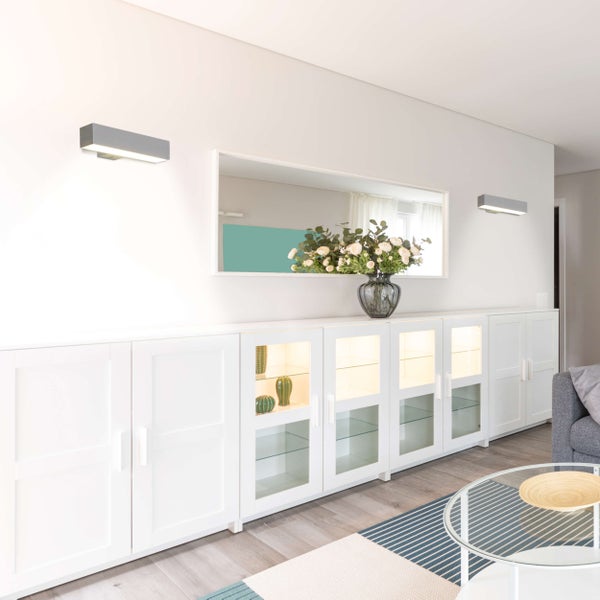 Wohnzimmer mit weißem Sideboard, Spiegel, Wandleuchten und Dekoration