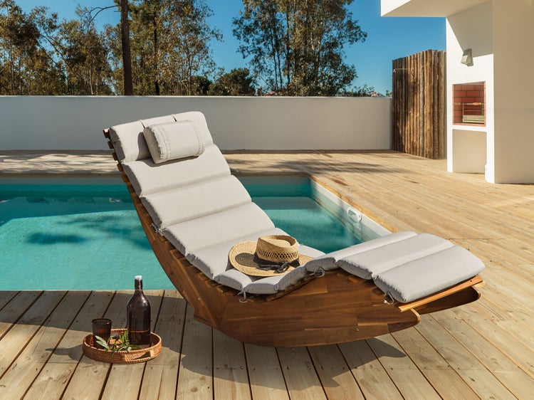 Szene mit einer Holzliege mit Auflage, einem Pool und einem Getränketablett im Freien