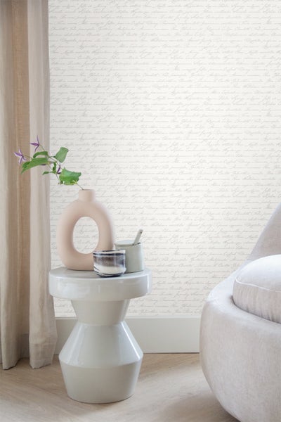 Dekorative Szene mit Vase, Becher und Hocker vor einer beschrifteten Tapete.