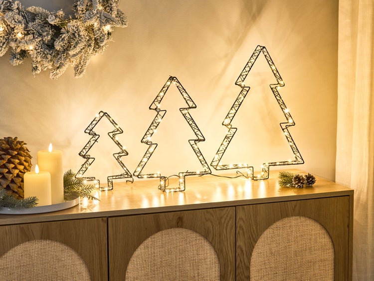 Dekorative beleuchtete Tannenbaumgruppe aus Metalldraht auf einer Kommode mit Kranz und Kerzen