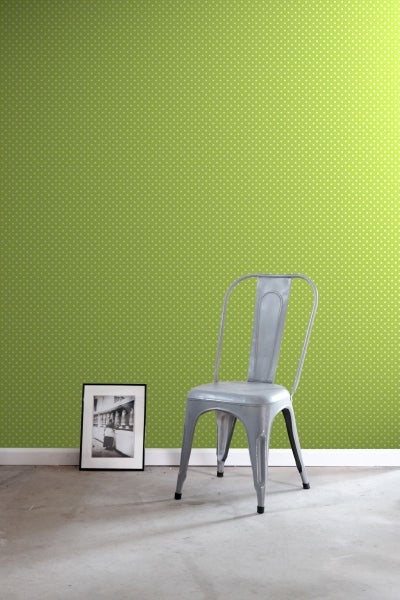 Zimmer mit grüner Punktmuster-Tapete, Metallstuhl und gerahmtem Bild