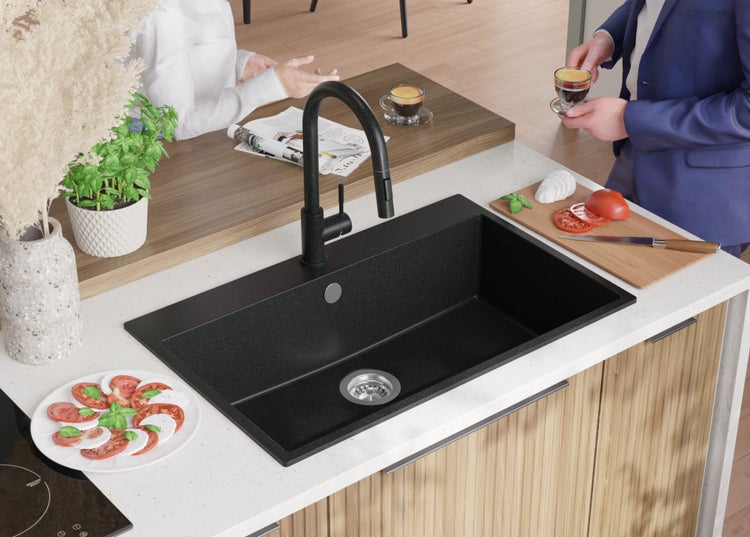 Küchenszene mit schwarzem Spülbecken, Armatur und Speisen auf der Arbeitsplatte.