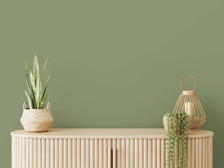 Holz-Sideboard mit gerippter Front, dekoriert mit einer Zimmerpflanze im Flechtkorb und einer Bambuslaterne mit Kerze.