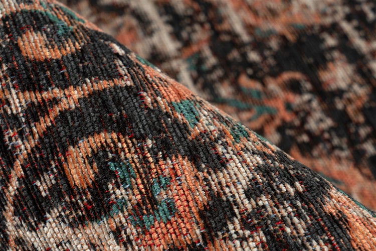 Detailaufnahme eines gewebten Teppichs mit Vintage-Muster in Schwarz, Orange und Grün.