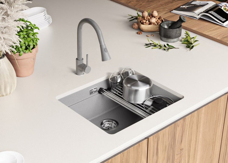 Küchenspüle mit Abtropfgestell, Wasserhahn und Küchenutensilien auf einer Küchentheke