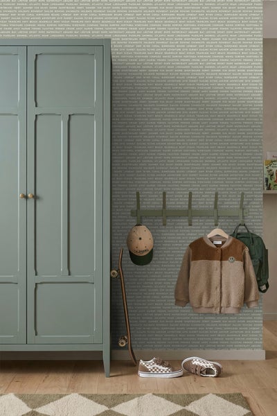 Grüner Kleiderschrank neben einer grünen Wandgarderobe mit Jacke und Rucksack, ein Skateboard an der Wand und Schuhe auf dem Boden.