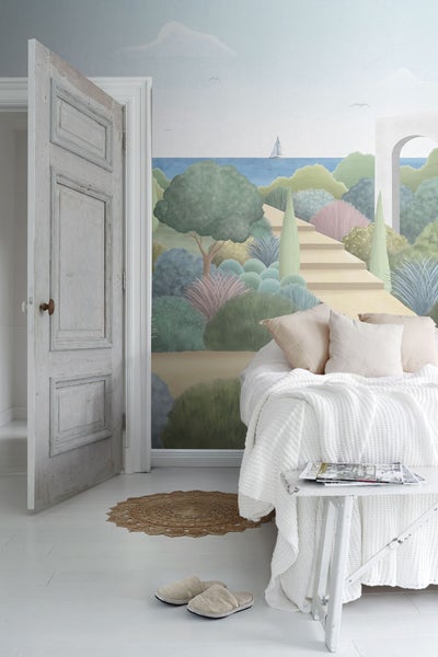 Helles Schlafzimmer mit Wandbild, Bett, Beistelltisch und offen stehender Tür