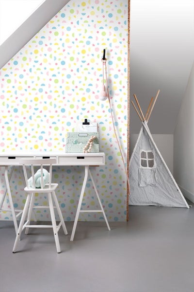 Kinderzimmer mit weißem Schreibtisch, Stuhl und Tipi vor einer Wand mit buntem geometrischem Kreismuster.