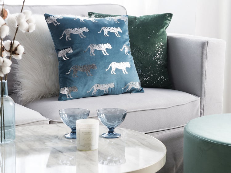 Interieuransicht mit blauem Sofa, rundem Spiegel und Stehlampe