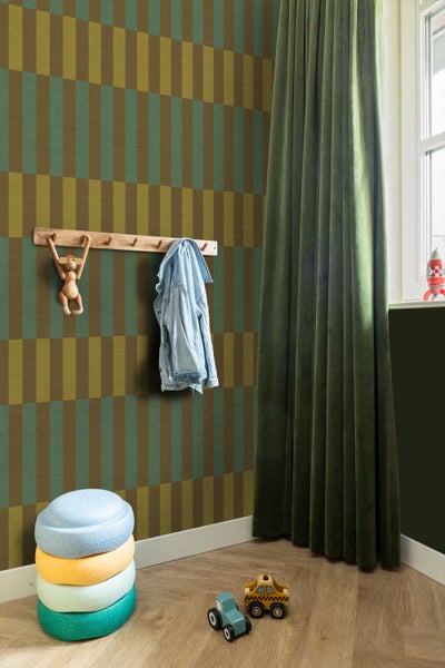 Kinderzimmer mit geometrisch gemusterter Tapete, Wandgarderobe aus Holz, grünem Samtvorhang und Spielzeug auf Parkettboden.