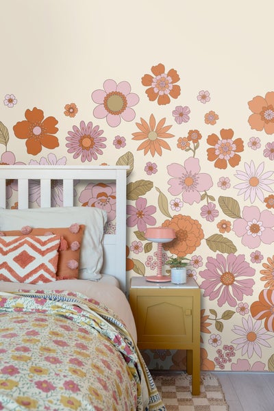 Schlafzimmer mit weißem Bett, gemusterten Kissen und floraler Tapete im Retro-Stil