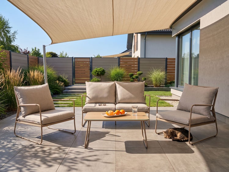 Moderne Terrasse mit Garten-Lounge-Set aus Sesseln, Sofa und Tisch unter einem großen Sonnensegel, umgeben von einem Garten mit Zaun.