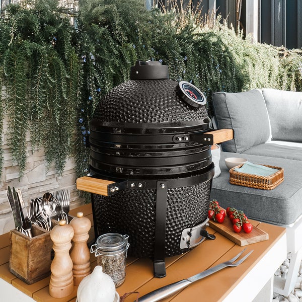 Keramikgrill auf einer Terrasse mit Grillbesteck und Zutaten