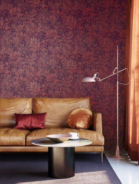 Wohnzimmer mit gemusterter Tapete, Sofa, Tisch und Stehlampe.