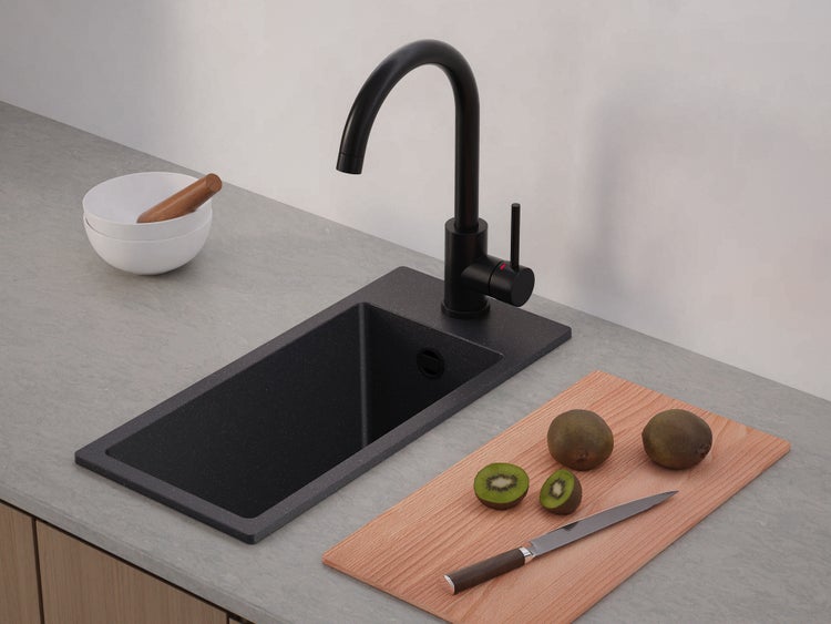 Moderne Küche mit dunkler Granitspüle und hoher schwarzer Armatur auf grauer Arbeitsplatte.