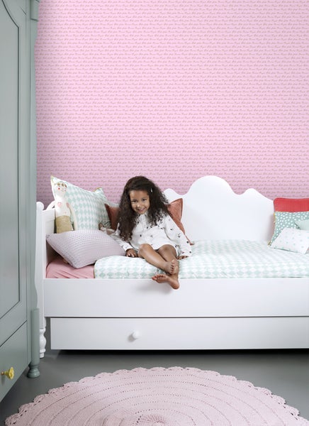 Kinderzimmer mit gemusterter Tapete, weißem Bett und rundem Teppich