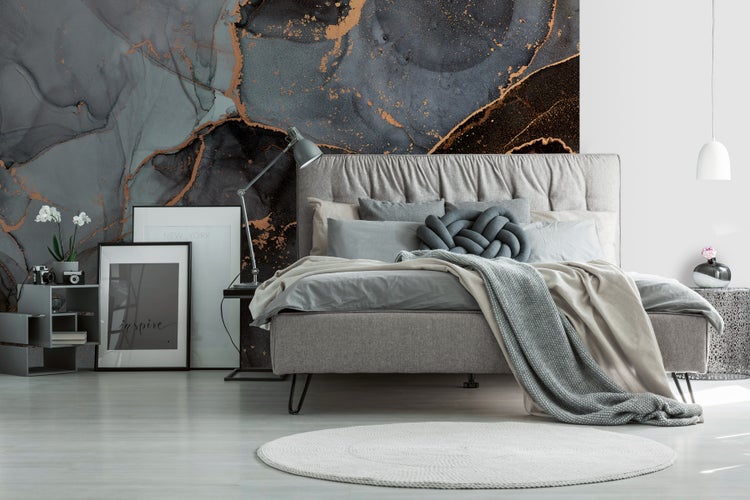 Schlafzimmer mit Bett, Nachttisch und dekorativer Wandtapete im Marmorstil.