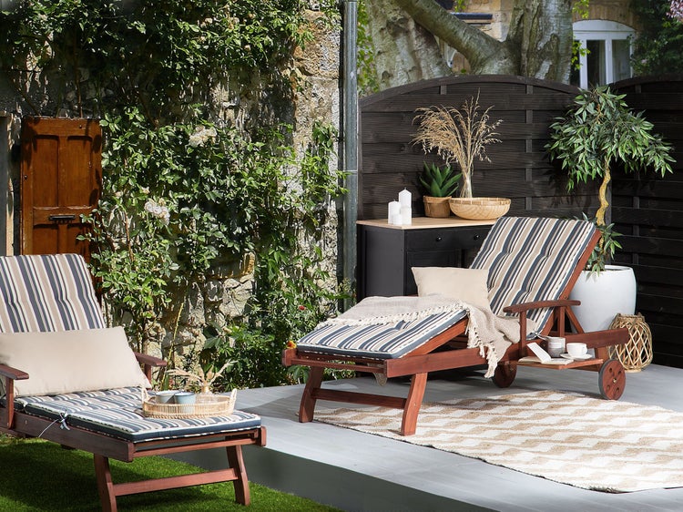 Szene mit zwei Holzliegen mit gestreiften Auflagen im Gartenbereich