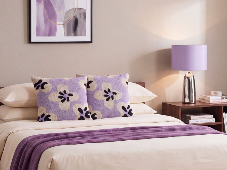 Modernes Schlafzimmer mit gemusterten Dekokissen, Überwurf, Nachttischleuchte und Wandbild in abgestimmter Gestaltung für ein harmonisches Ambiente.