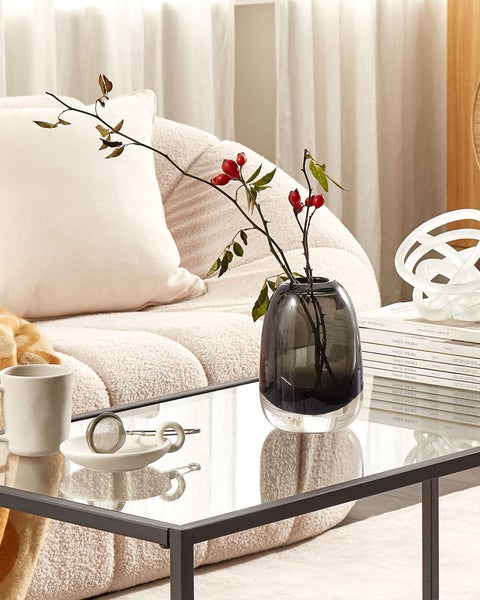 Wohnzimmerszene mit Sofa, Couchtisch, Vase und Dekorationsgegenständen.