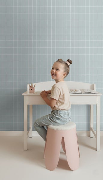 Helles Kinderzimmer mit weißem Schreibtisch, Hocker und blau karierter Tapete