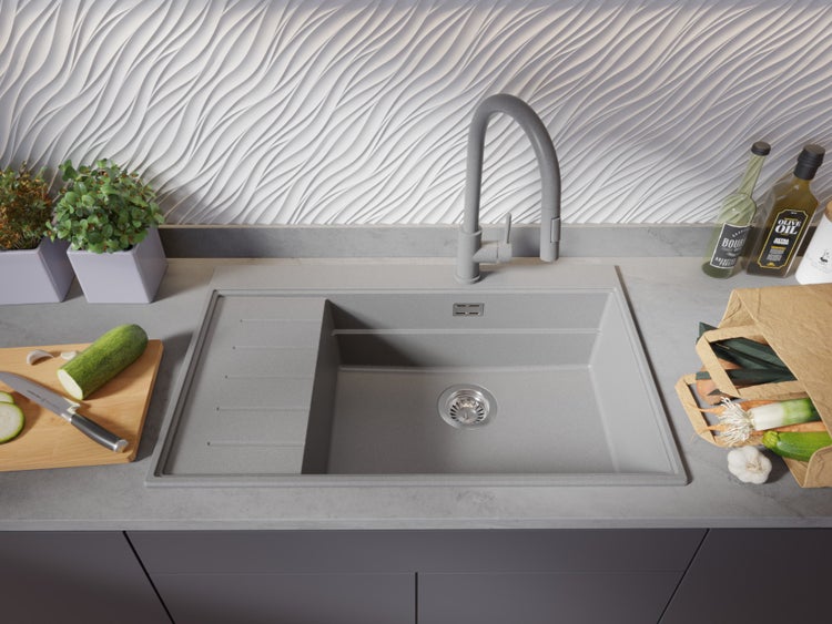 Spüle aus Steingut mit Abtropffläche, Armatur und Gemüse auf einer Küchentheke.