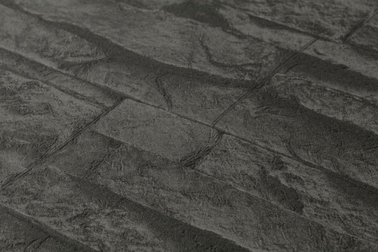 Dekorative Wohnraumgestaltung mit einer Tapete in Steinoptik hinter einer Sitzbank.