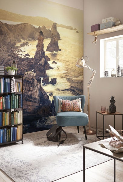 Wohnzimmer mit Fototapete mit Meereslandschaft, Sessel, Stehlampe und Bücherregal