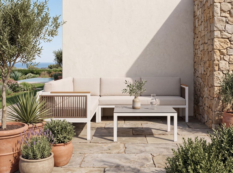 Moderne Ecklounge aus Metall und Seilgeflecht mit passendem Loungetisch auf einer Steinterrasse in einer mediterranen Gartenumgebung