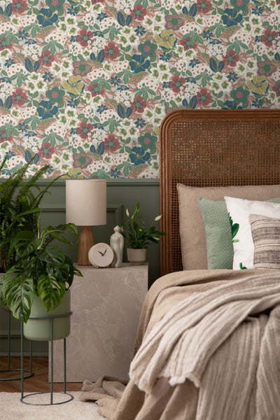 Einladendes Schlafzimmer mit floral gemusterter Tapete, offenstehender Holztür und Tagesdecke