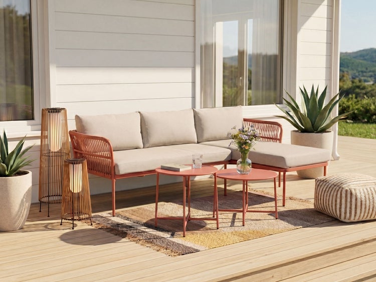 Modernes Garten-Lounge-Set auf einer Holzterrasse mit Ecksofa, beigen Polstern, zwei runden Beistelltischen, Teppich und Außenleuchten.