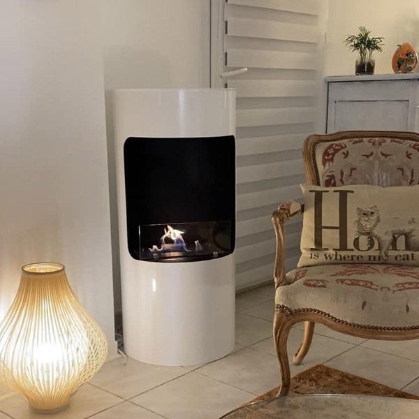 Ein Zimmer mit einem Bioethanolkamin, einer Lampe und einem Stuhl.