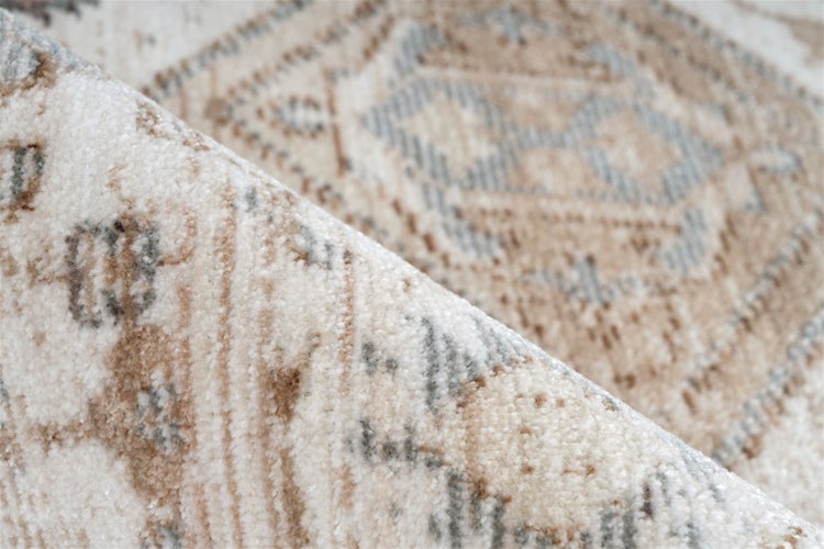 Detailansicht eines gemusterten Teppichs mit umgeknickter Ecke, Textur und geometrisches Design.