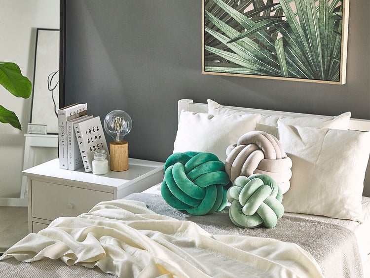 Schlafzimmer-Szene mit Bett, dekorativen Knoten-Kissen und Nachttisch