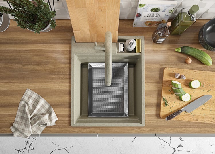 Küchenspüle mit Abtropfschale, Armatur und Spülmittelspender auf einer Küchentheke mit Schneidebrett und Zutaten