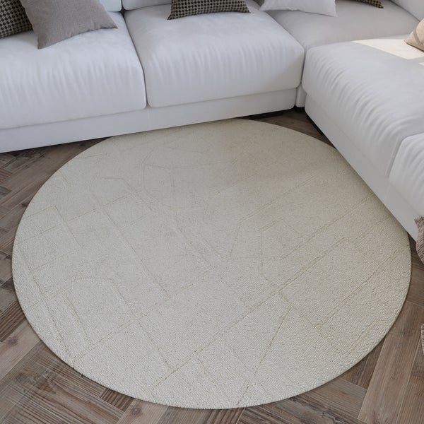 Runder Teppich mit dezentem geometrischem Muster auf Parkettboden vor einem hellen Sofa.