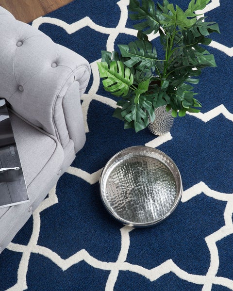 Detailansicht eines blauen Teppichs mit weißem Muster und gewebter Rückseite