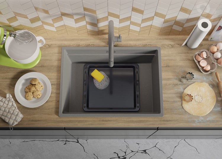 Küchenszene mit Spüle, Armatur, Backblech, Schwamm, Teig, Ausstechformen, Eiern und Küchenmaschine.