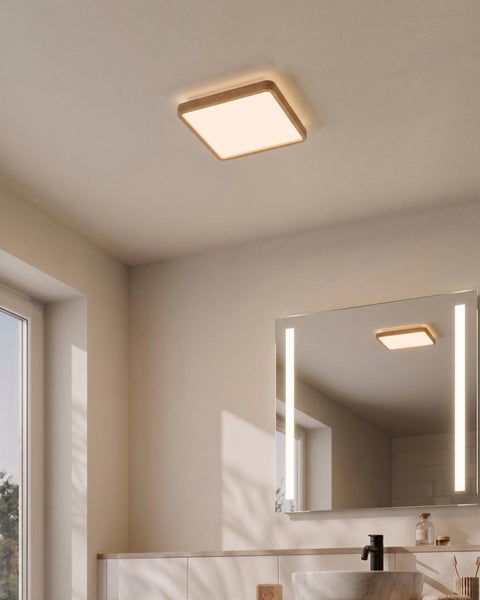 Quadratische LED Deckenleuchte mit Holzrahmen in einem hellen Badezimmer mit Badspiegel und Waschbecken.