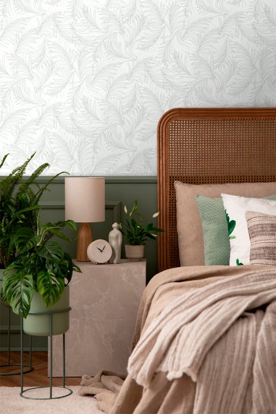 Schlafzimmer mit gemusterter Tapete, Rattankopfteil und Pflanzen