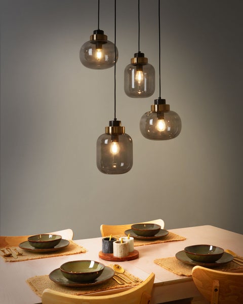 Esstisch mit Gedeck und vier grauen Glaspendelleuchten.