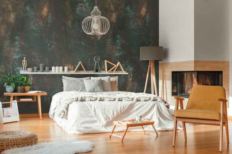 Schlafzimmer mit Bett, Sessel und Kamin für eine gemütliche Atmosphäre