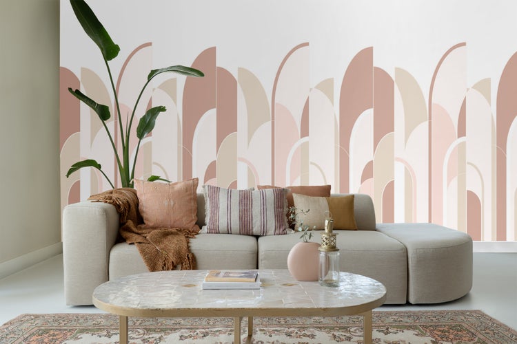 Helles Wohnzimmer mit Sofa, Kissen, Couchtisch und dekorativer Zimmerpflanze vor einer gemusterten Wand