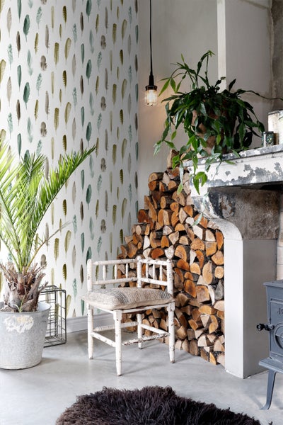 Wohnzimmer mit Feder-Tapete, Kaminholzstapel und Zimmerpflanzen für eine gemütliche Atmosphäre