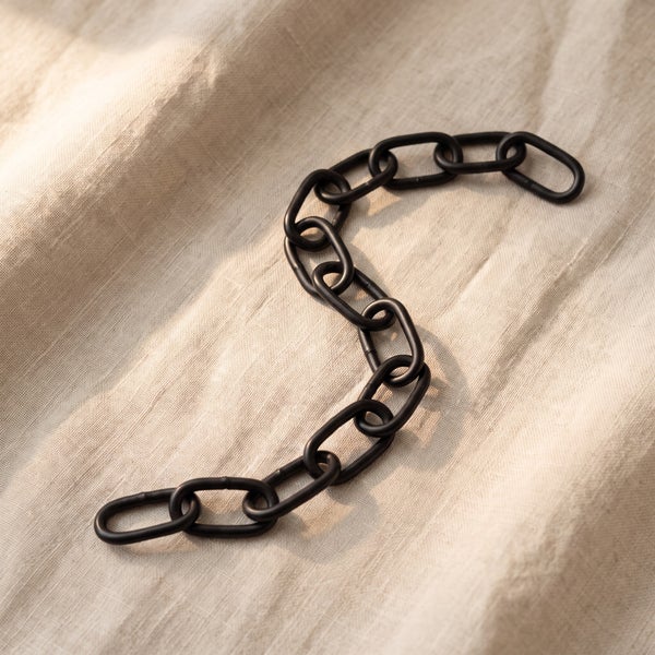 Eine Metallkette mit ovalen Gliedern auf einem strukturierten Stoffuntergrund.