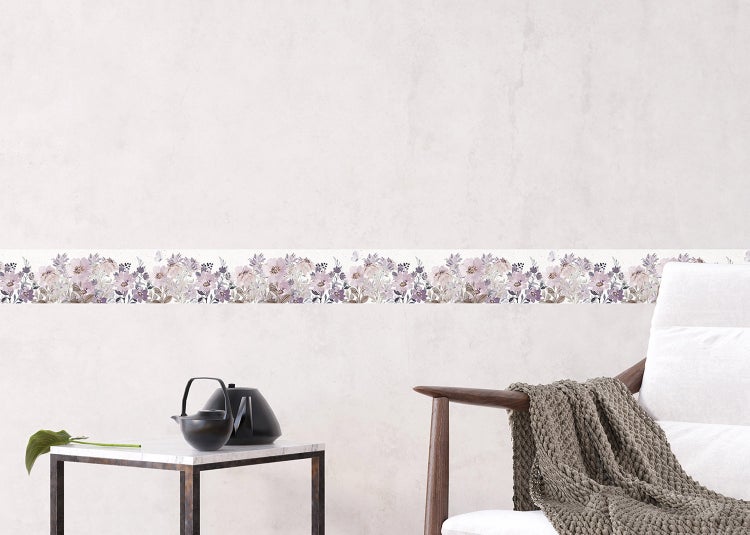 Tapetenbordüre mit floralem Muster an einer hellen Wand in einem modern eingerichteten Zimmer mit Sessel und Beistelltisch.