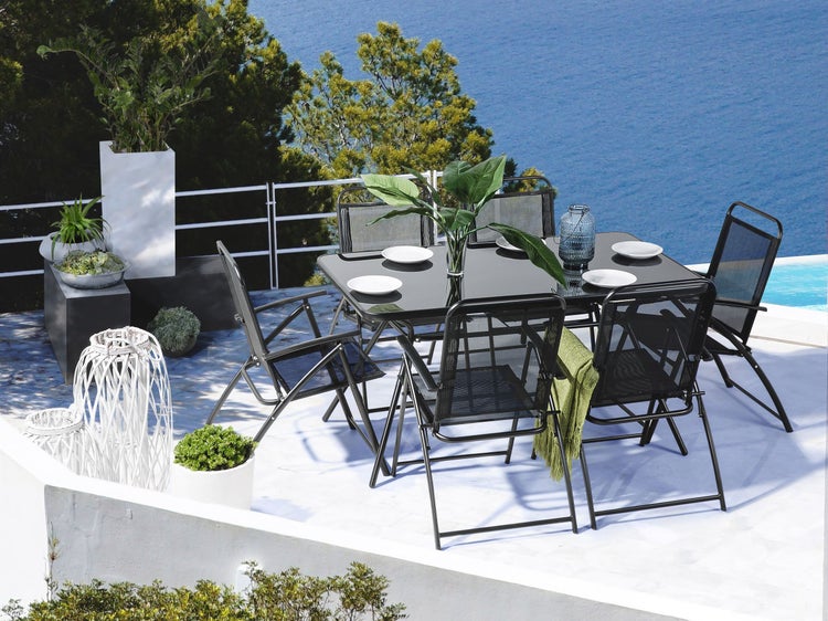 Gartensitzgruppe mit Tisch, Stühlen, Geschirr und dekorativen Pflanzen im Außenbereich