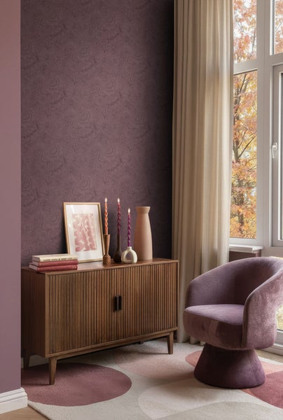 Helles Zimmer mit Holzkommode, Sessel und gemusterter Tapete