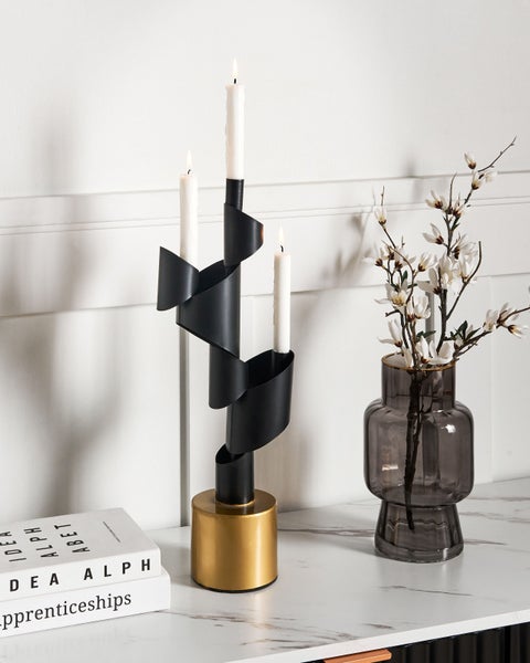 Kerzenständer mit drei weißen Kerzen, Blumenvase und Bücher auf einem Tisch