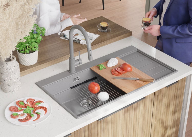 Küchenszene mit Spüle, Armatur, Schneidebrett und Lebensmitteln auf einer Küchentheke.